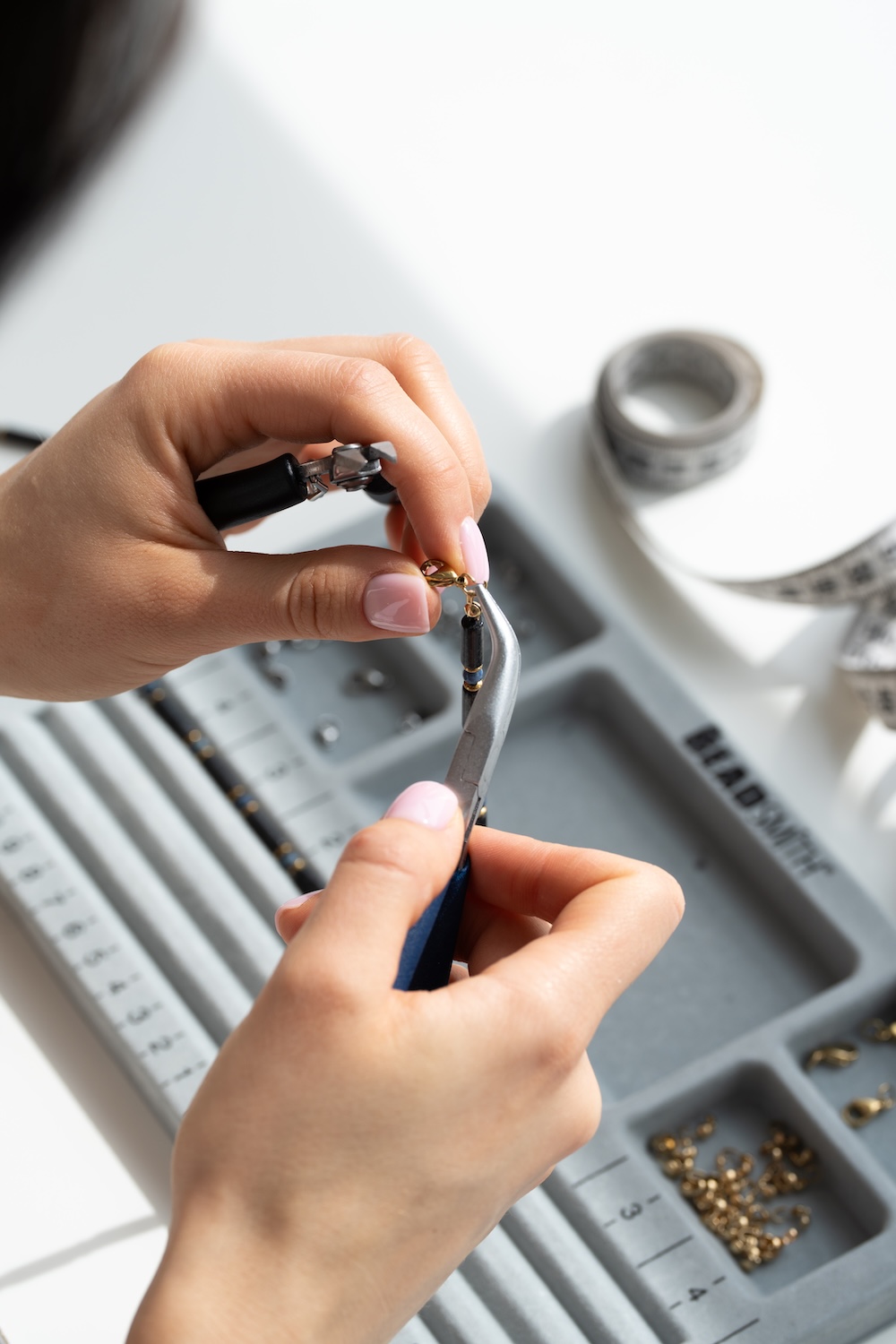 Osoba ręcznie tworzy biżuterię przy użyciu narzędzi jubilerskich.