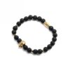 Bransoletka z czarnych koralików z motywem złotej czaszki.