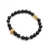 Bransoletka z czarnymi koralikami i złotymi akcentami w kształcie czaszki.