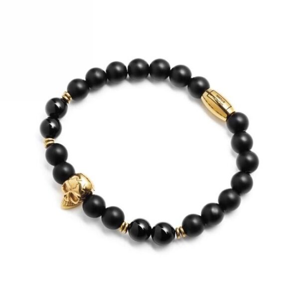 Bransoletka z czarnymi koralikami i złotymi akcentami w kształcie czaszki.