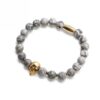Bransoletka z szarymi kulkami i złotą czaszką.