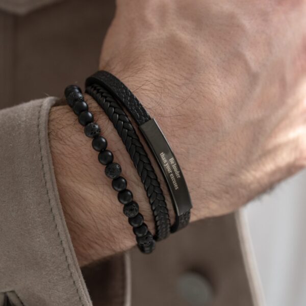 Męska ręka z czarnymi bransoletkami.