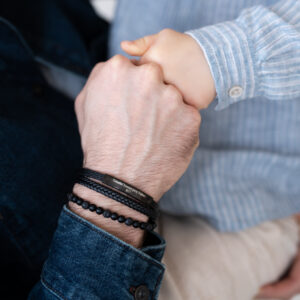 Osoba w niebieskiej koszuli trzyma za rękę mniejsze dziecko.