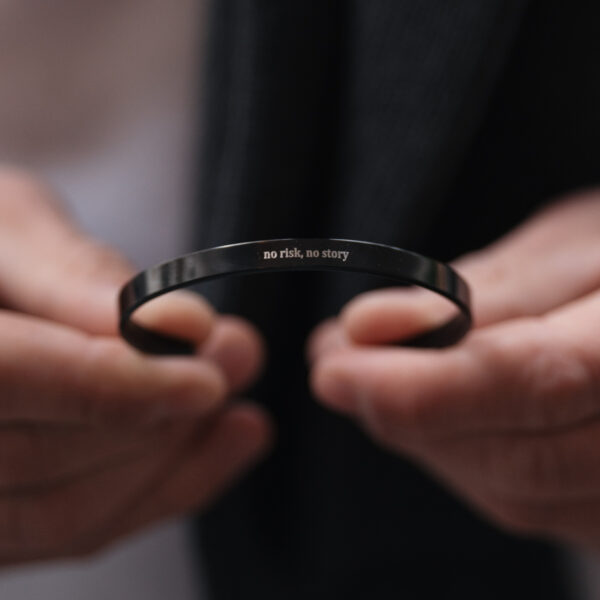 Metalowa bransoletka z wygrawerowanym napisem 'no risk, no story'.