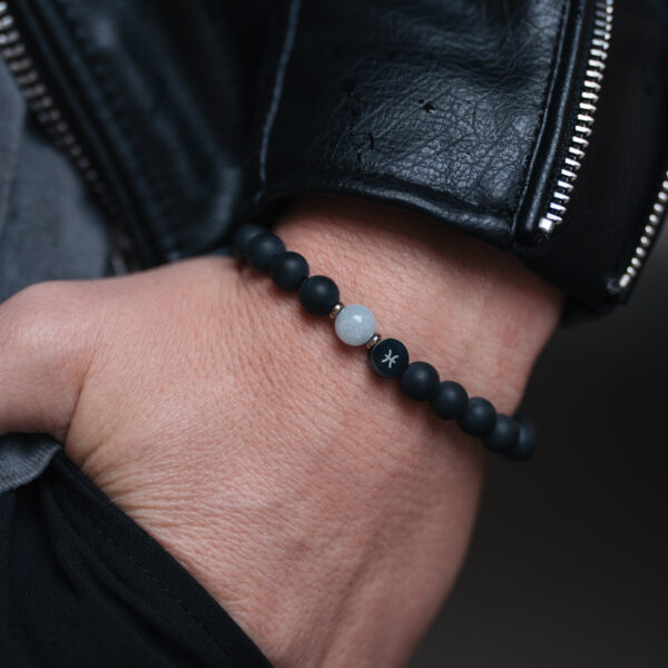 Bransoletka z czarnych koralików na nadgarstku z kurtką skórzaną.