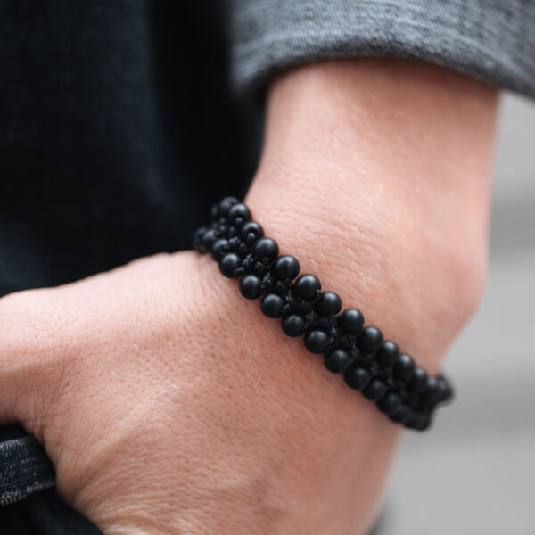 Czarna bransoletka z koralików na nadgarstku.
