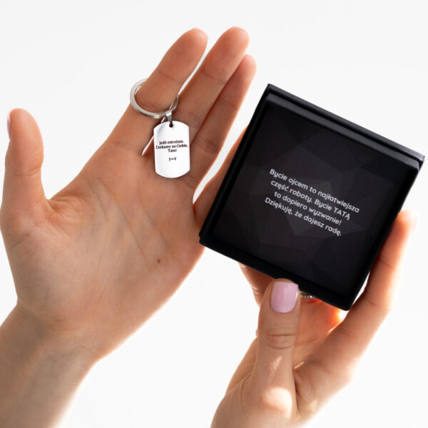 Osoba trzyma brelok i pudełko z tekstem dedykacji dla taty.
