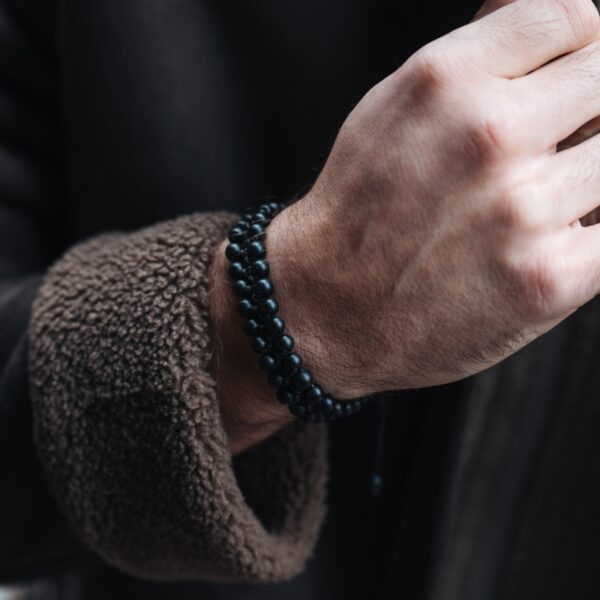 Mężczyzna noszący czarną bransoletkę z koralików na nadgarstku.