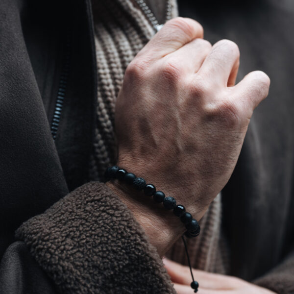 Osoba nosząca bransoletkę z czarnych koralików.