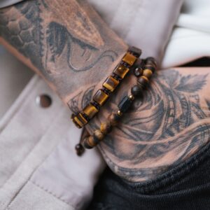 Tatuaż na ramieniu z bransoletkami z drewnianych koralików.