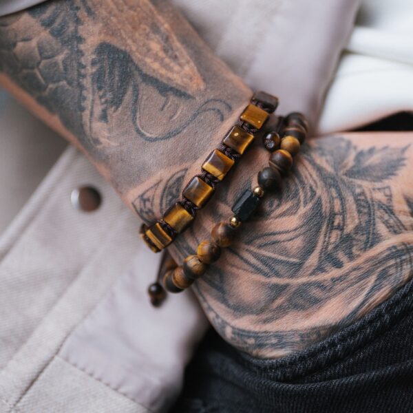 Tatuaż na ramieniu z bransoletkami z drewnianych koralików.