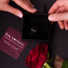 Naszyjnik w czarnym pudełku i czerwona róża. Obok kartka z napisem: Gdy kochasz, świat zmienia się na zawsze.