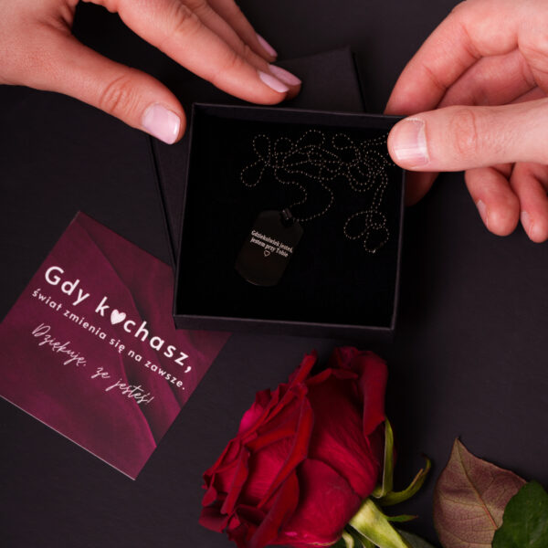 Naszyjnik w czarnym pudełku i czerwona róża. Obok kartka z napisem: Gdy kochasz, świat zmienia się na zawsze.