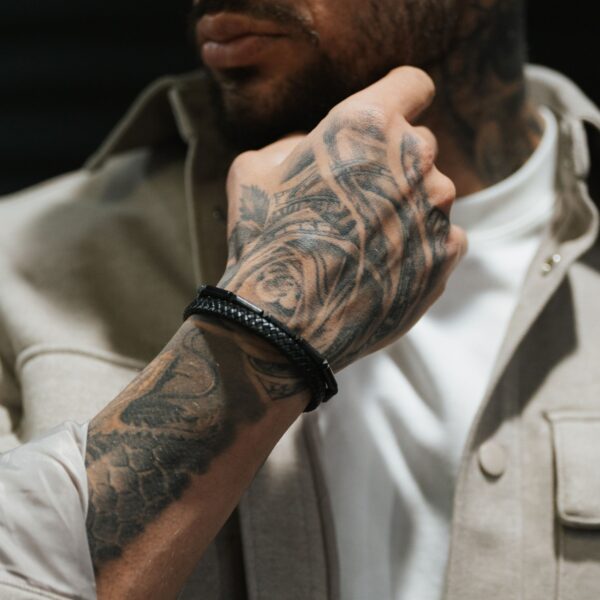 Zbliżenie na tatuaże na ręce mężczyzny w jasnej koszuli.