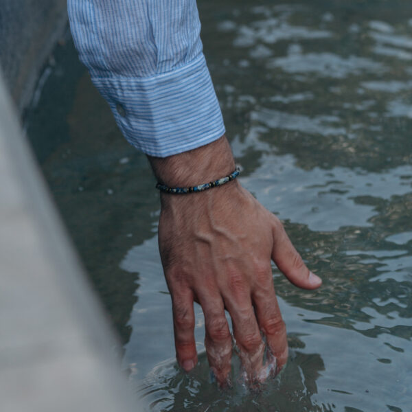 Męska ręka wchodząca do wody z niebieską koszulą.