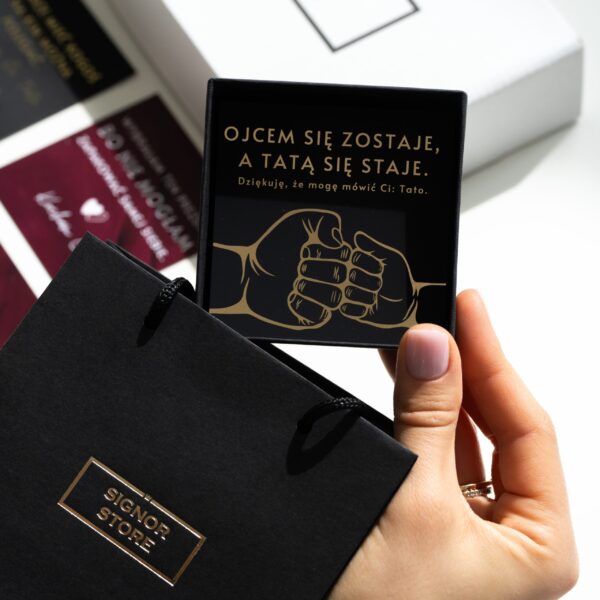 Osoba trzyma tabliczkę z napisem 'Ojcem się zostaje, a tatą się staje. Dziękuję, że mogę mówić Ci: Tato'.