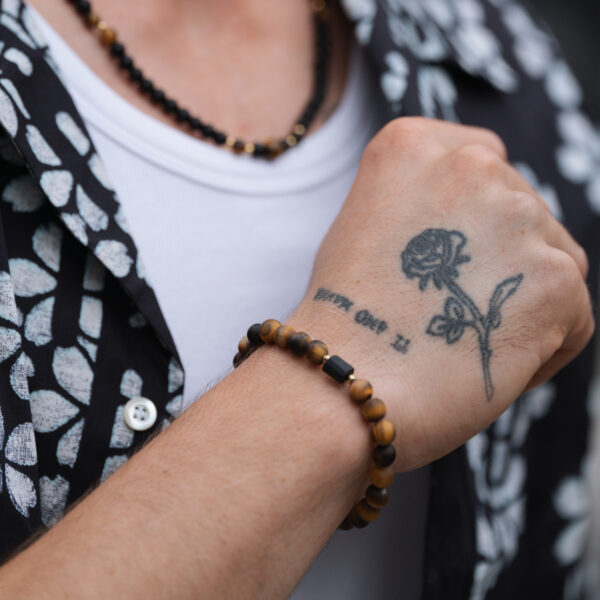 Ręka z tatuażem róży i bransoletką z koralików