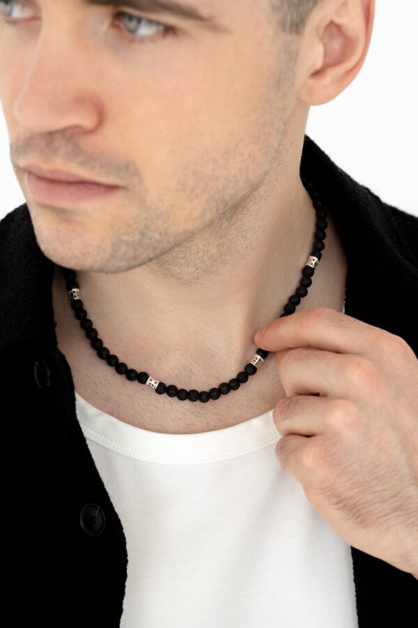 Mężczyzna noszący naszyjnik z czarnych koralików.