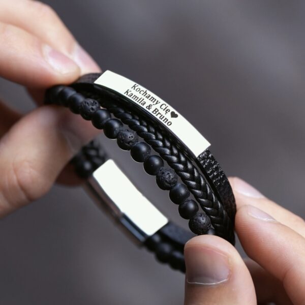 Czarna bransoletka z napisem 'Kochamy Cię ❤️ Kamila & Bruno' trzymana w dłoniach.