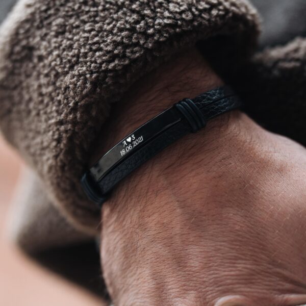 Skórzana bransoletka z wygrawerowaną datą i inicjałami na nadgarstku.