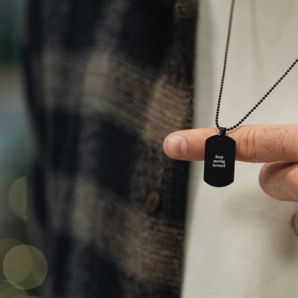 Osoba trzymająca naszyjnik z napisem 'Keep moving forward'.