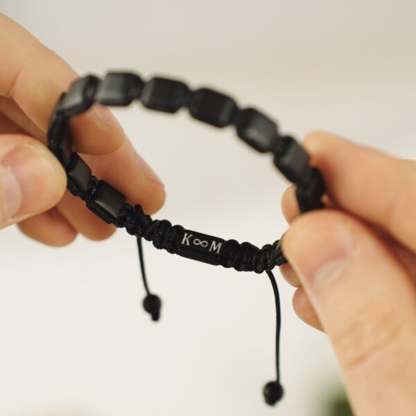 Czarna bransoletka z symbolem nieskończoności oraz literami K i M.