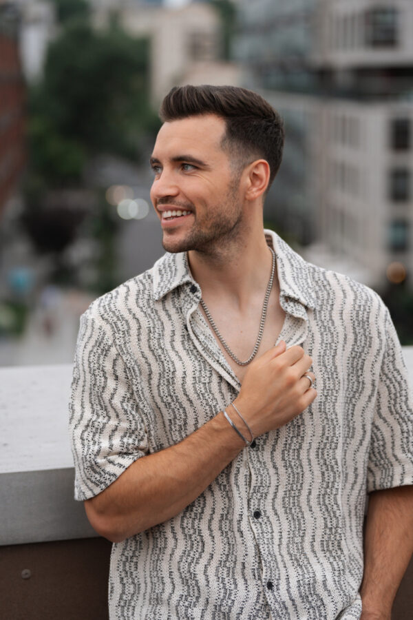 Mężczyzna w pasiastym ubraniu stojący na zewnątrz z uśmiechem