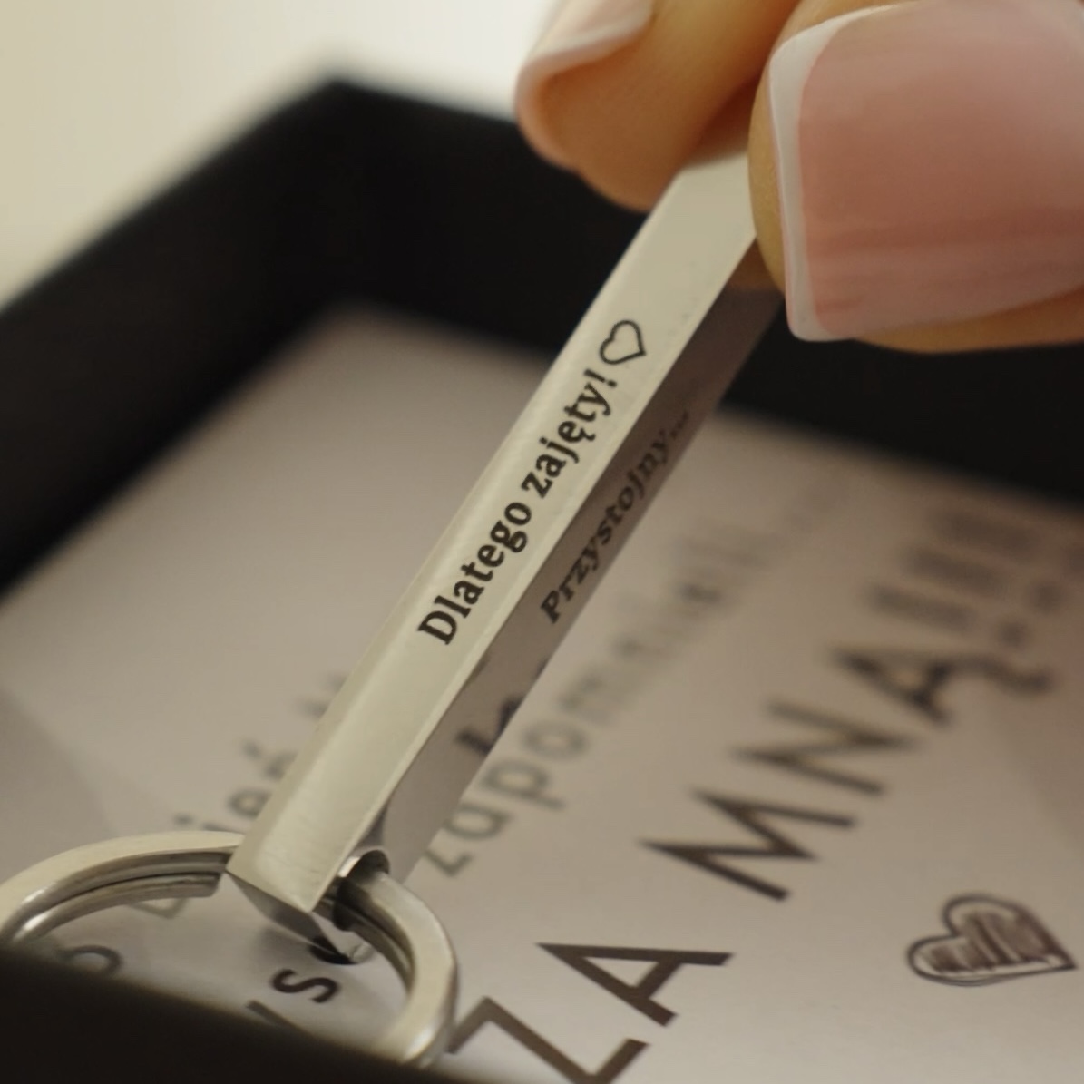 Brelok z grawerem 'Dlatego zajęty!' trzymany w dłoni.