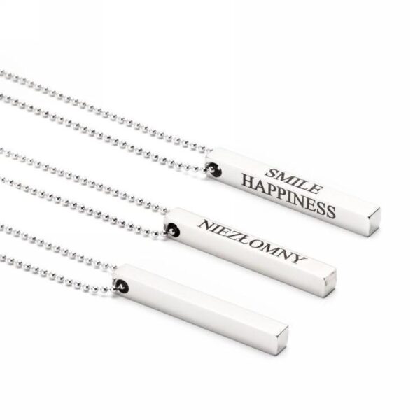 Trzy srebrne naszyjniki z napisami Smile, Happiness i Niezłomny.