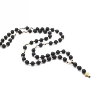 Czarny różaniec z krzyżykiem na białym tle.