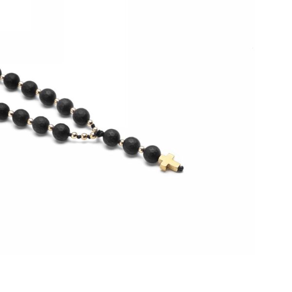 Czarny różaniec z drewnianym krzyżykiem na białym tle.