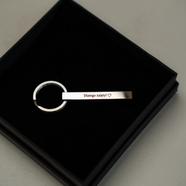 Brelok z napisem 'Dlatego zajęty!' i sercem, w pudełku.