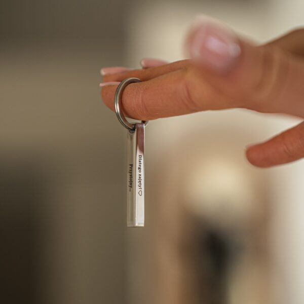 Metalowy brelok trzymany na palcu osoby.