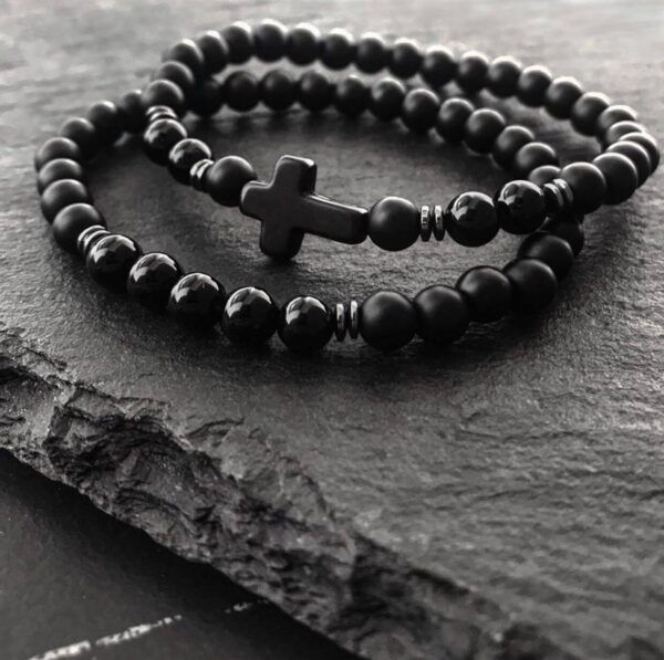 Czarne korale z krzyżem na ciemnym tle.