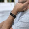 Mężczyzna nosi czarną koronkę z krzyżykiem na nadgarstku.