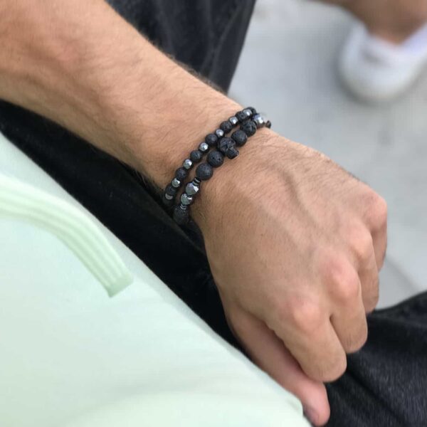 Zbliżenie na nadgarstek z dwoma czarnymi bransoletkami z koralików.