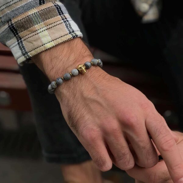 Męska dłoń z bransoletką z koralików i motywem czaszki.