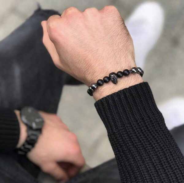 Męska ręka z czarną bransoletką z czaszką.
