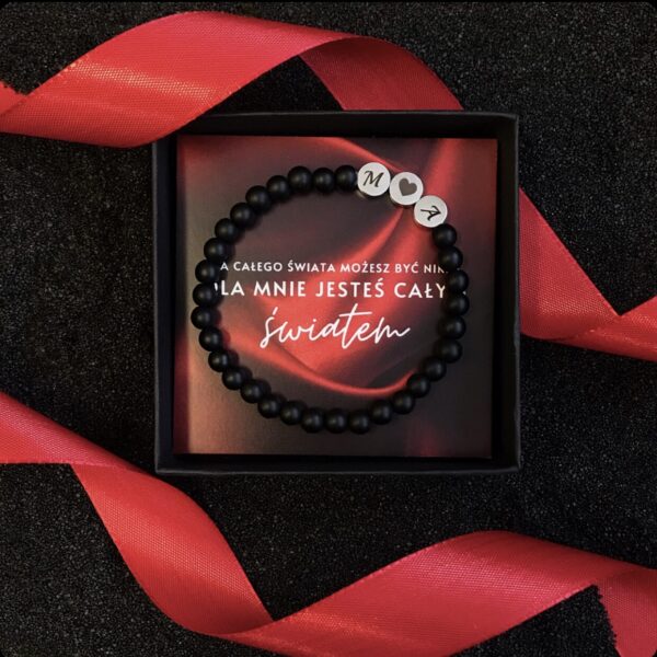 Bransoletka z czarnych koralików z literami M, sercem i A w ozdobnym pudełku z czerwonym napisem.