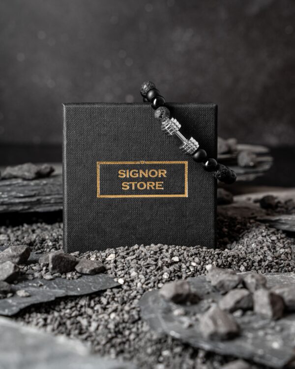 Czarne pudełko Signor Store z bransoletką na tle kamieni.