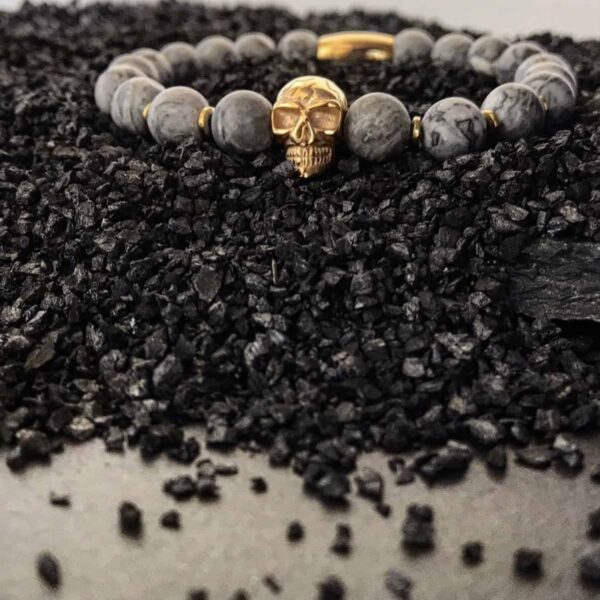 Bransoletka z czaszką na czarnym drobnym żwirze.