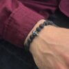 Osoba nosząca bransoletkę z czarnych kamieni z czaszką.