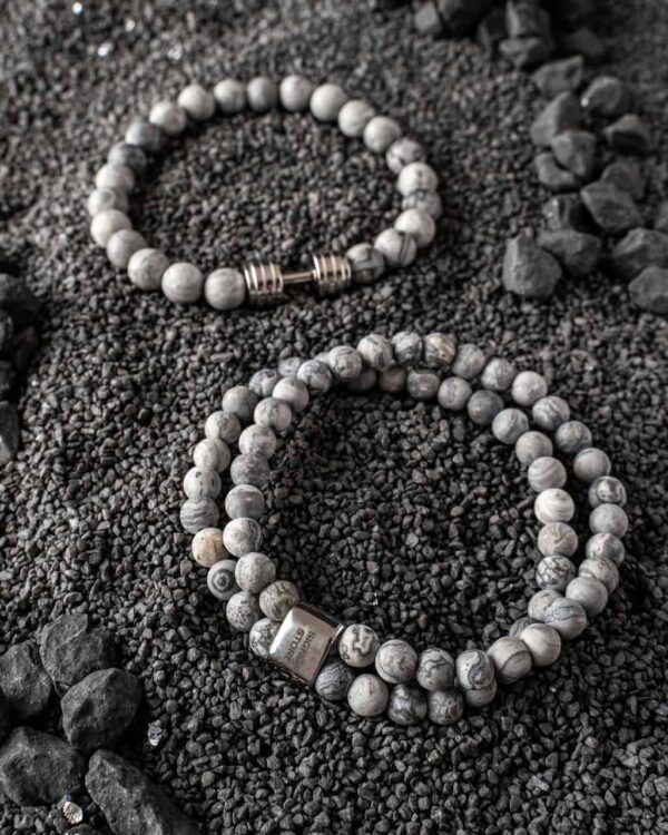 Dwie bransoletki z szarych koralików na czarnym żwirku.