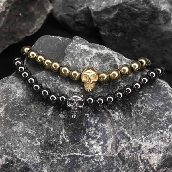 Dwie bransoletki z czaszkami na tle kamieni.