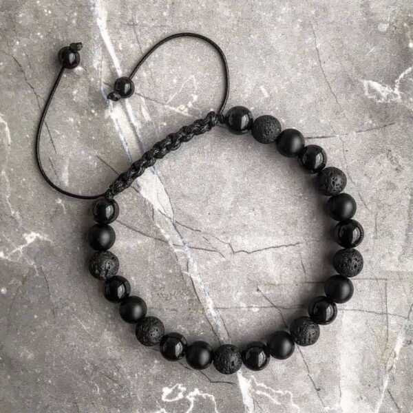 Bransoletka z czarnych koralików na szarym tle.