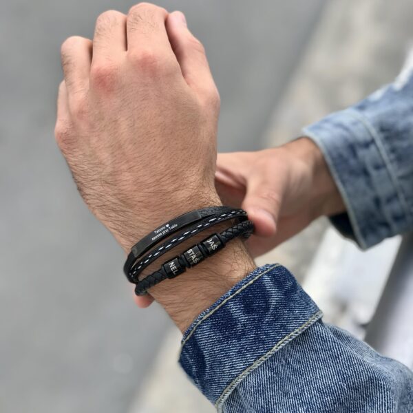 Ręka z założonymi stylowymi bransoletkami z napisami.