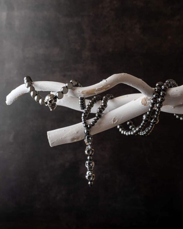 Korale z czaszkami zawieszone na białej gałęzi.