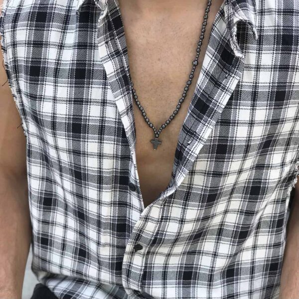Mężczyzna w rozpiętej koszuli w kratę z naszyjnikiem z krzyżem.