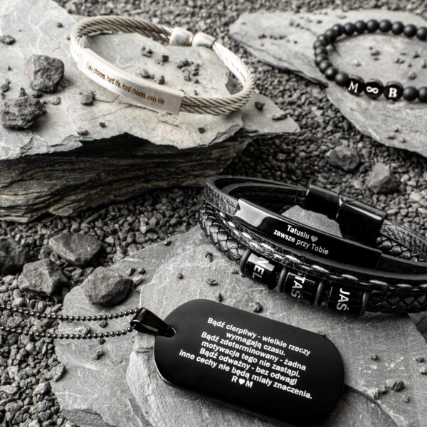 Biżuteria męska na kamieniach: metalowe bransoletki z grawerem oraz naszyjnik z napisem.
