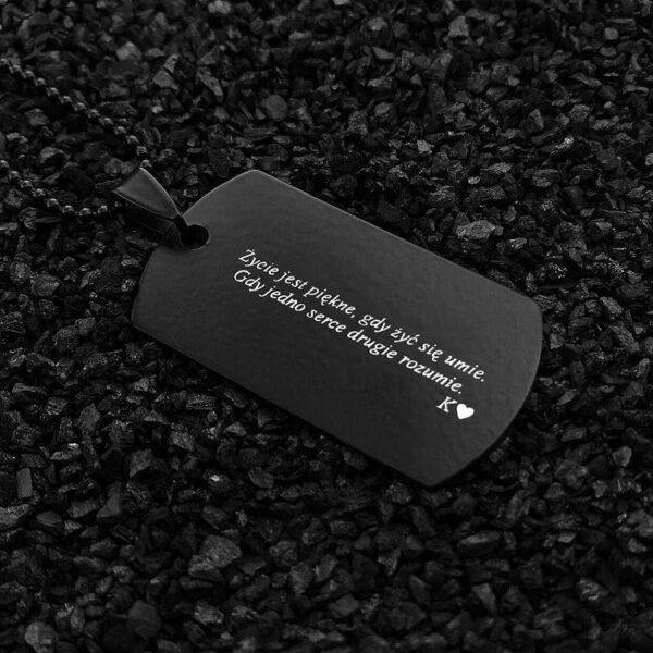 Czarna zawieszka z wygrawerowanym napisem: 'Życie jest piękne, gdy żyć się umie. Gdy jedno serce drugie rozumie.'